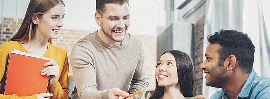 Vier Auszubildende im Gespräch mit Laptop und Tablet