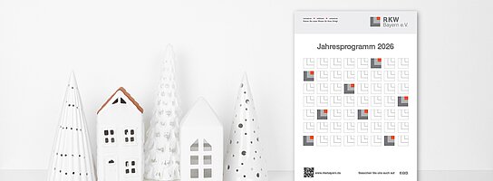 Weiße Dekohäuser und -Bäume sowie das RKW Jahresprogramm vor weißen Hintergrund